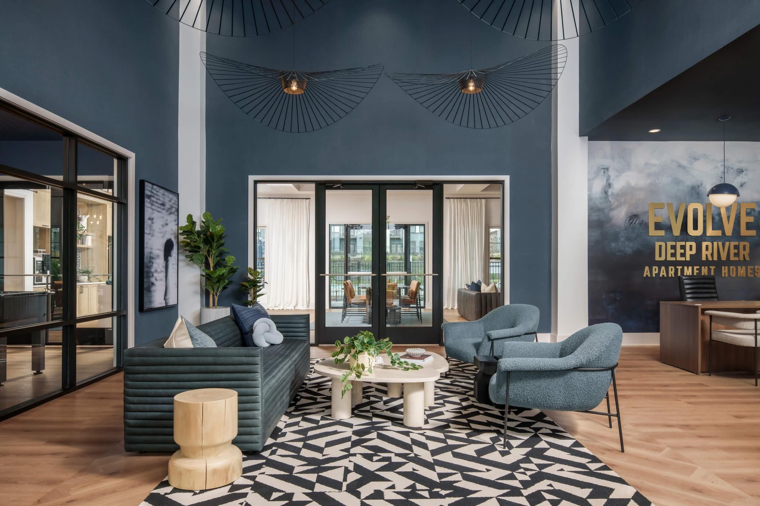 Evolve Deep River modern lounge with blue walls, geometric rug, stylish seating, and large windows letting in natural light.